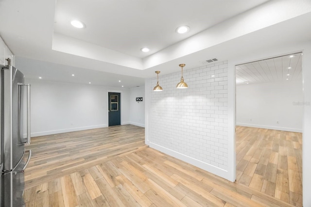 empty room with a raised ceiling and light hardwood / wood-style floors