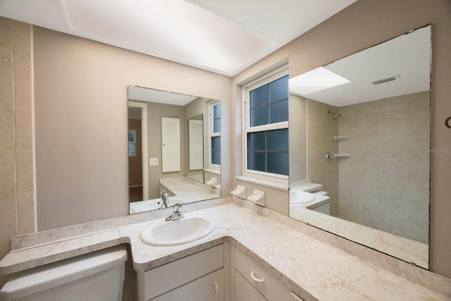 bathroom with vanity, toilet, and tiled shower