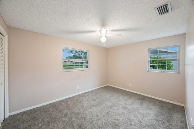 interior space with a closet, ceiling fan, carpet, and a textured ceiling