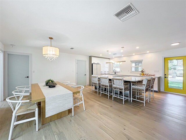 dining area with plenty of natural light, sink, and light hardwood / wood-style flooring