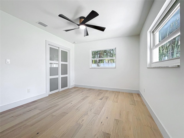 spare room featuring baseboards, visible vents, ceiling fan, and light wood finished floors