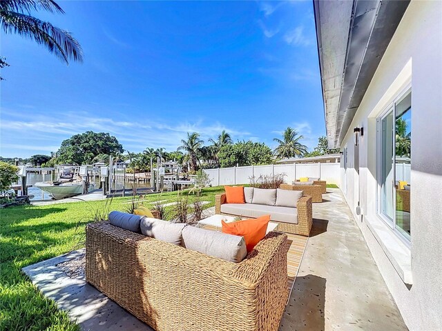 view of patio with fence, boat lift, a boat dock, and an outdoor hangout area