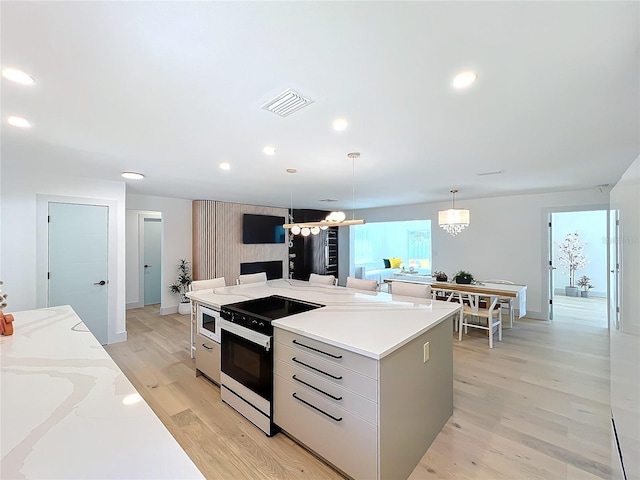 kitchen featuring a center island, pendant lighting, recessed lighting, visible vents, and light wood-style flooring