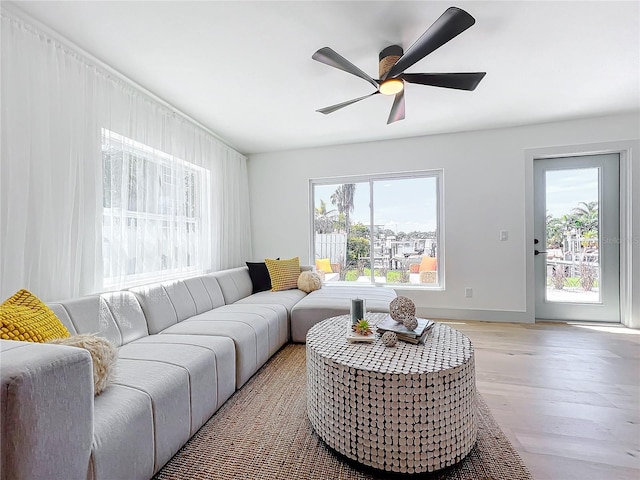 living room featuring baseboards, light wood finished floors, a wealth of natural light, and a ceiling fan