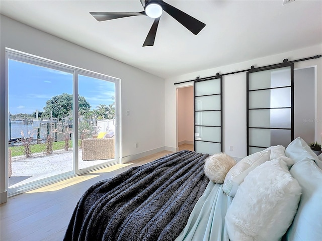 bedroom featuring a water view, ceiling fan, and a barn door