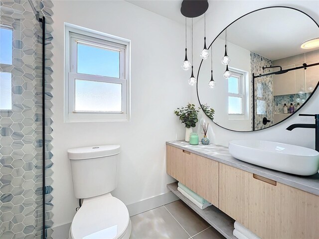 bathroom featuring a wealth of natural light, vanity, toilet, and tiled shower