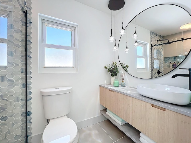 bathroom featuring toilet, vanity, tiled shower, baseboards, and tile patterned floors