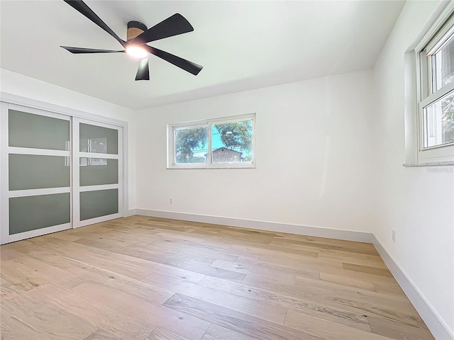 empty room with a wealth of natural light, ceiling fan, and light hardwood / wood-style floors