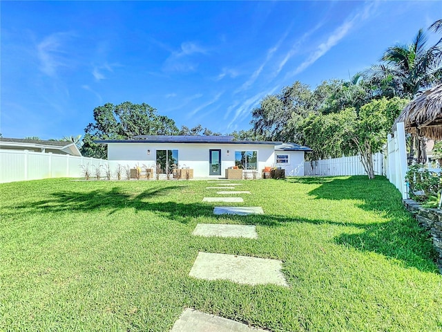 rear view of house with a lawn, a fenced backyard, and stucco siding