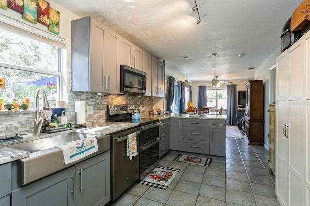 kitchen featuring gray cabinets, stainless steel appliances, kitchen peninsula, and tasteful backsplash