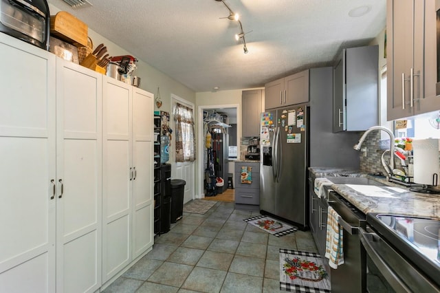 kitchen with sink, tasteful backsplash, a textured ceiling, gray cabinets, and appliances with stainless steel finishes