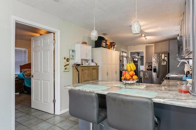 kitchen featuring stainless steel refrigerator with ice dispenser, hanging light fixtures, a textured ceiling, and light tile patterned flooring