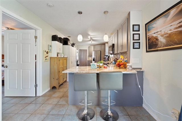 kitchen with stainless steel appliances, decorative light fixtures, a breakfast bar, and kitchen peninsula