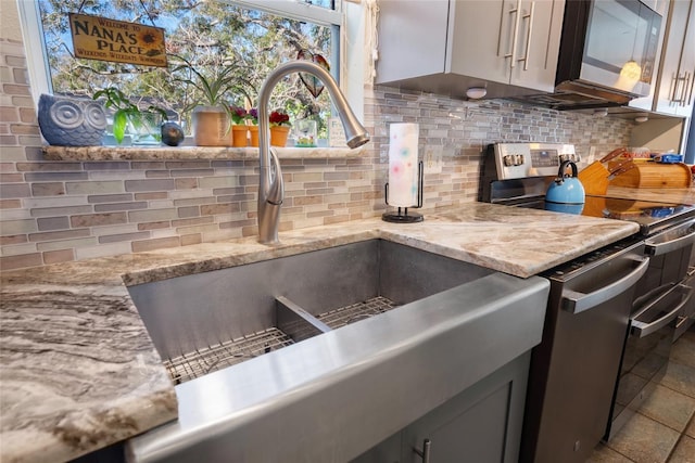 kitchen with light stone counters, appliances with stainless steel finishes, sink, and backsplash