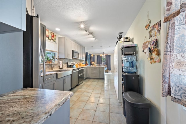 kitchen featuring sink, light tile patterned floors, gray cabinets, appliances with stainless steel finishes, and decorative backsplash