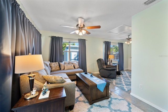 living room with ceiling fan, a textured ceiling, and a wealth of natural light