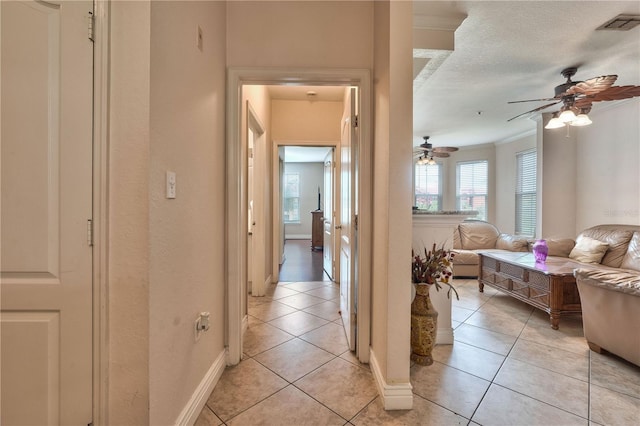 hall with a textured ceiling and light tile patterned flooring