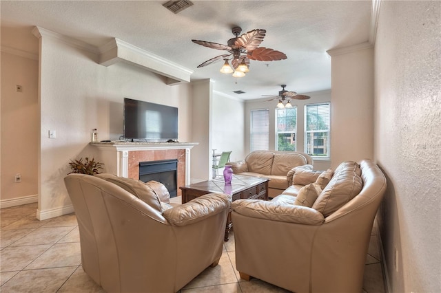 living room featuring a fireplace, ornamental molding, a textured ceiling, ceiling fan, and light tile patterned flooring