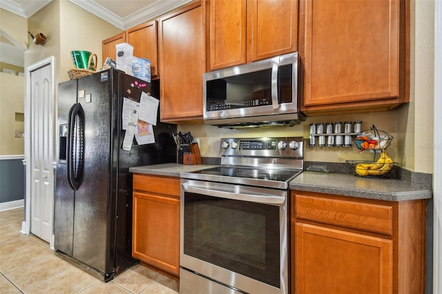 kitchen featuring light tile patterned floors, appliances with stainless steel finishes, brown cabinetry, dark countertops, and crown molding