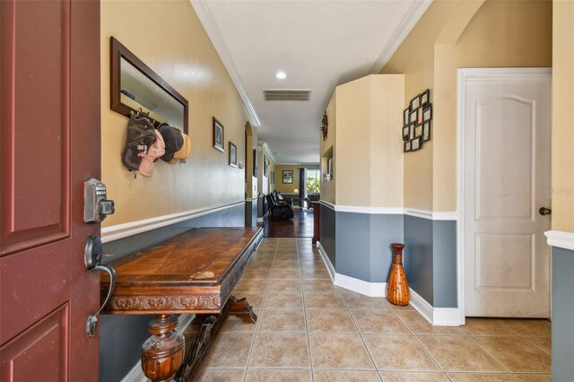 corridor featuring light tile patterned floors, recessed lighting, visible vents, baseboards, and ornamental molding