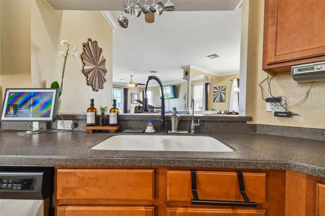 kitchen with dishwasher, dark countertops, a sink, and crown molding