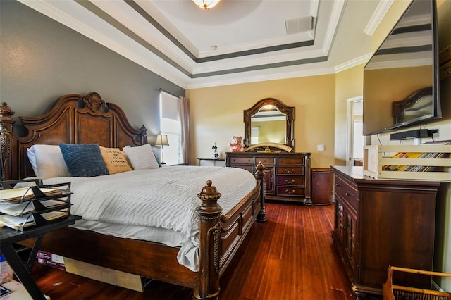 bedroom featuring dark wood-style floors, visible vents, a tray ceiling, and crown molding