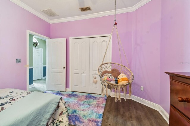 bedroom featuring baseboards, wood finished floors, visible vents, and crown molding