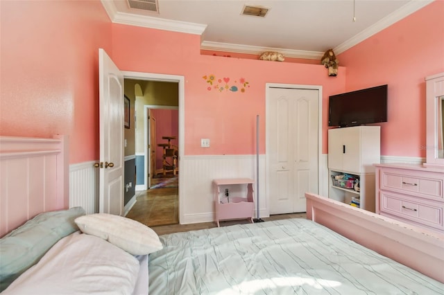 bedroom featuring a wainscoted wall, visible vents, and crown molding