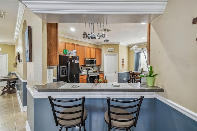 kitchen featuring stainless steel appliances, visible vents, ornamental molding, and light tile patterned floors