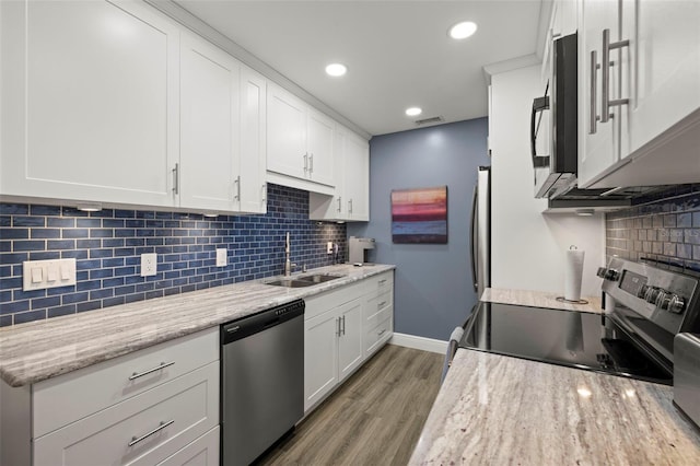 kitchen featuring light hardwood / wood-style flooring, stainless steel appliances, white cabinetry, sink, and tasteful backsplash