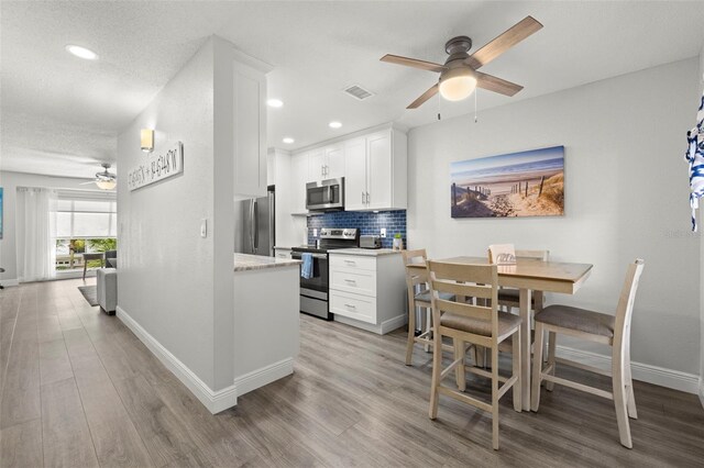 dining area with light wood-type flooring, a textured ceiling, and ceiling fan