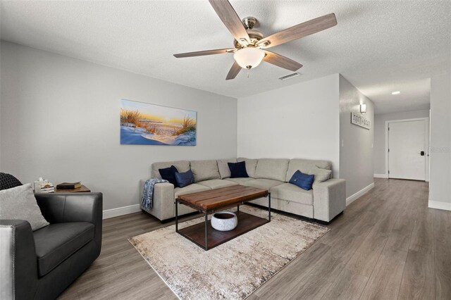 living room featuring a textured ceiling, ceiling fan, and hardwood / wood-style flooring