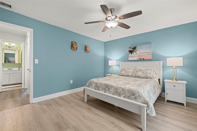 bedroom with ceiling fan, ensuite bath, and light hardwood / wood-style flooring