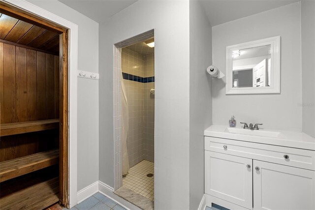 bathroom with tiled shower, vanity, and tile patterned floors