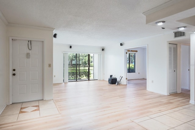 unfurnished living room with ornamental molding, a textured ceiling, and light hardwood / wood-style floors