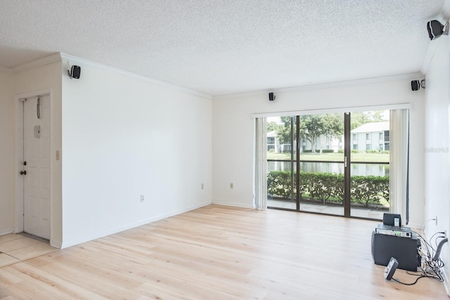 empty room with light wood-type flooring, crown molding, a textured ceiling, and a water view