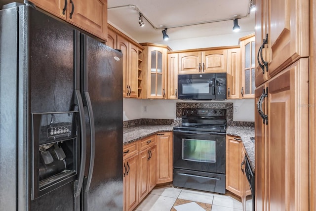 kitchen featuring dark stone countertops, black appliances, light tile patterned flooring, and track lighting