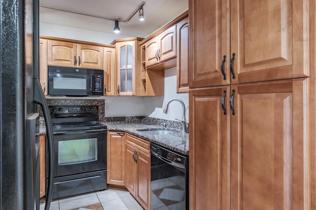 kitchen featuring dark stone countertops, sink, black appliances, light tile patterned flooring, and rail lighting