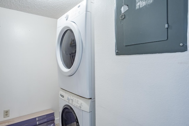 clothes washing area featuring stacked washer and dryer and a textured ceiling