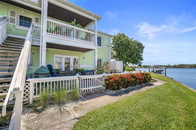 view of property exterior with a lawn, a water view, a balcony, and stucco siding