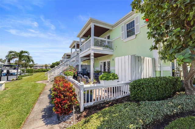 view of property exterior with a balcony, a yard, and stucco siding