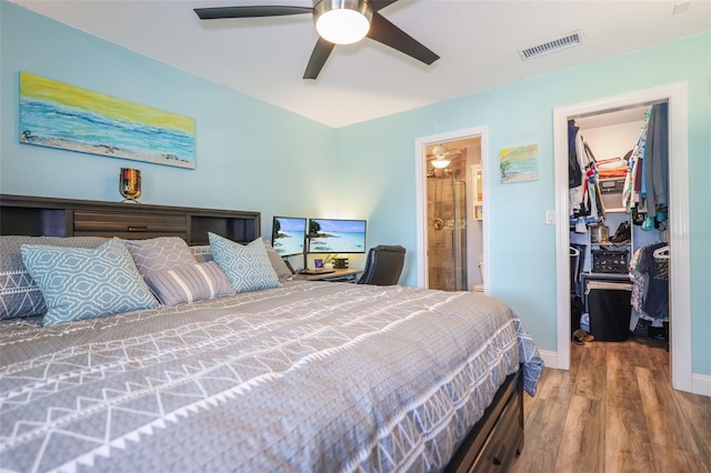 bedroom featuring visible vents, ensuite bath, wood finished floors, a walk in closet, and a closet