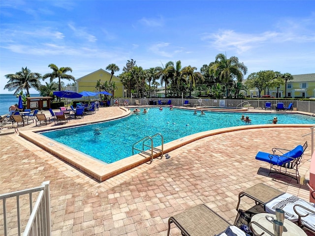 community pool featuring fence and a patio