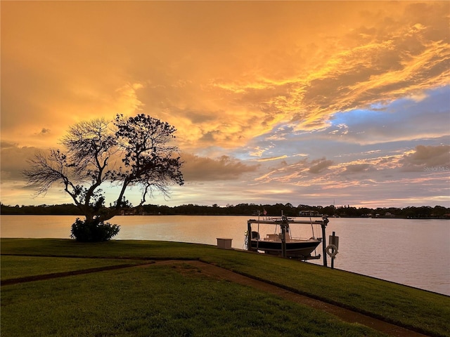 dock area featuring a water view, boat lift, and a lawn