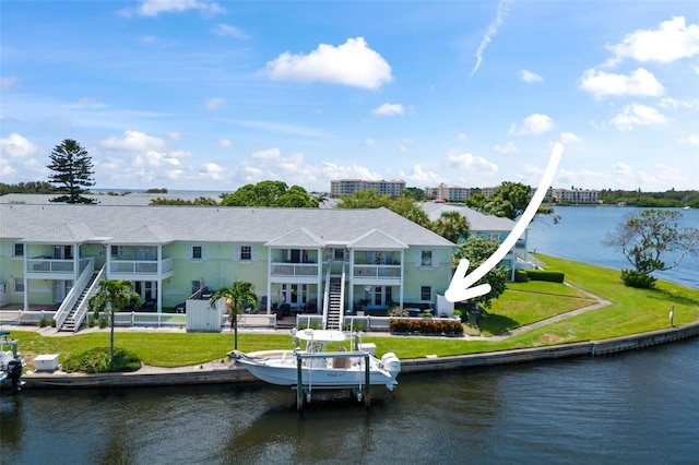 rear view of property with a yard, a water view, stairway, fence, and a balcony