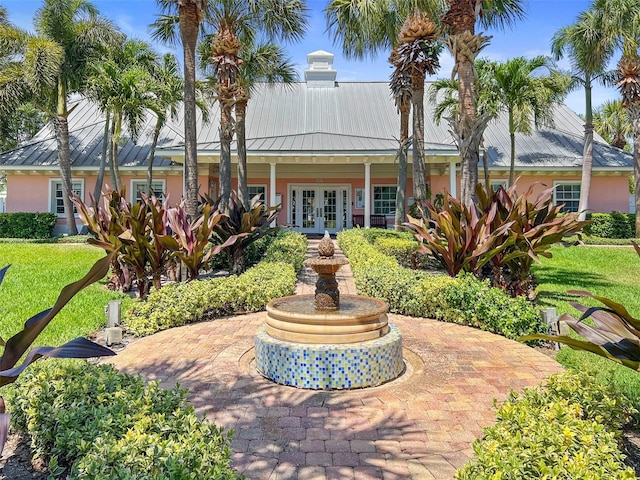 view of front facade with french doors, metal roof, and stucco siding