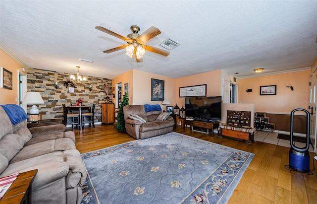 living room with wood-type flooring, a textured ceiling, ceiling fan with notable chandelier, and crown molding