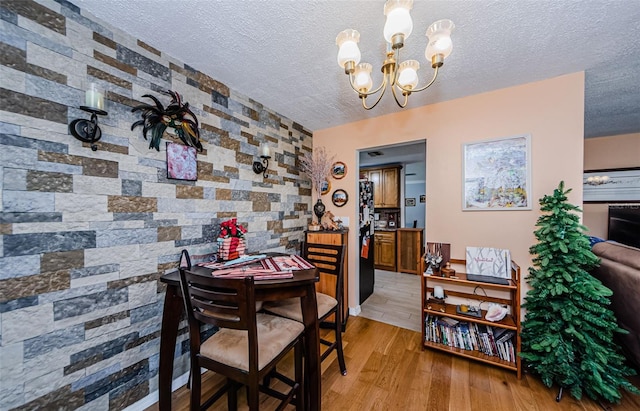 2208 Citrus Valley Cir, Palm Harbor, FL 34683 - dining area featuring a textured ceiling, an accent wall, a chandelier, and light wood-type flooring