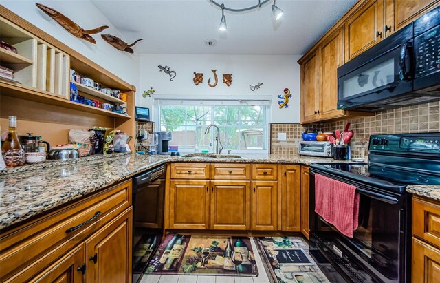 kitchen featuring backsplash, black appliances, light stone counters, and sink