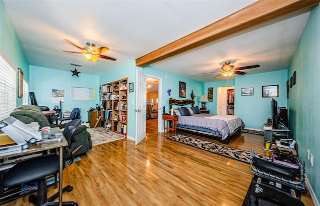 bedroom with wood-type flooring, beamed ceiling, and ceiling fan